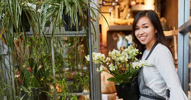 A women working in a flower shop, smile in her face.